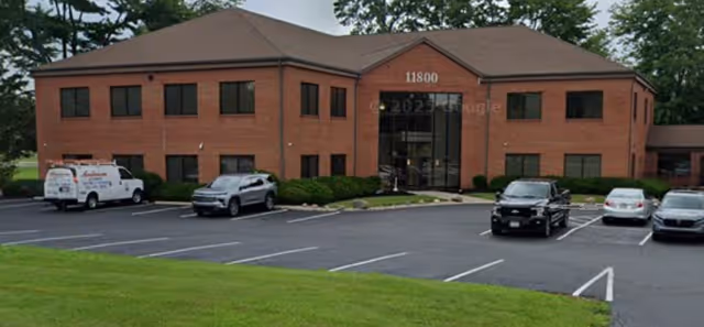 Brick senior living facility with a glass entry and a parking lot in front.