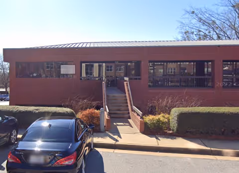 Red-brick senior living facility exterior with central entrance staircase and parked cars
