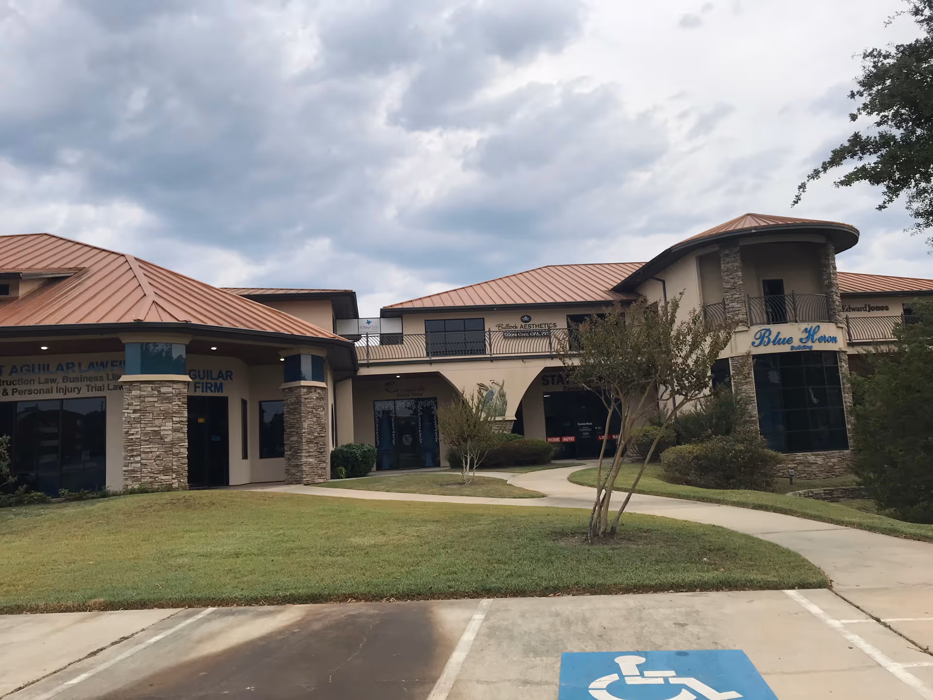 Exterior view of a strip mall building with storefronts and a wheelchair parking space.