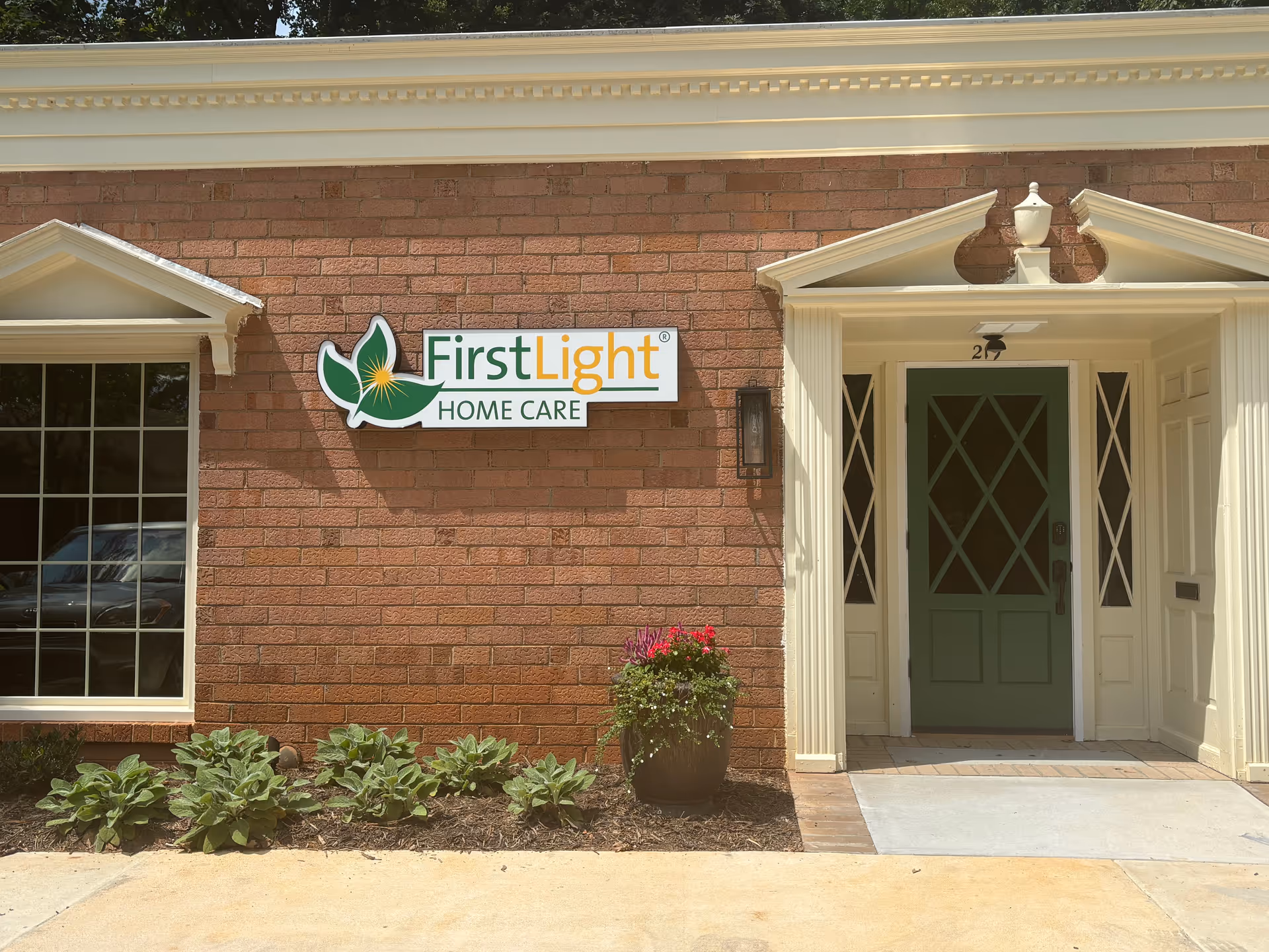 Brick building facade with FirstLight Home Care sign and green front door.