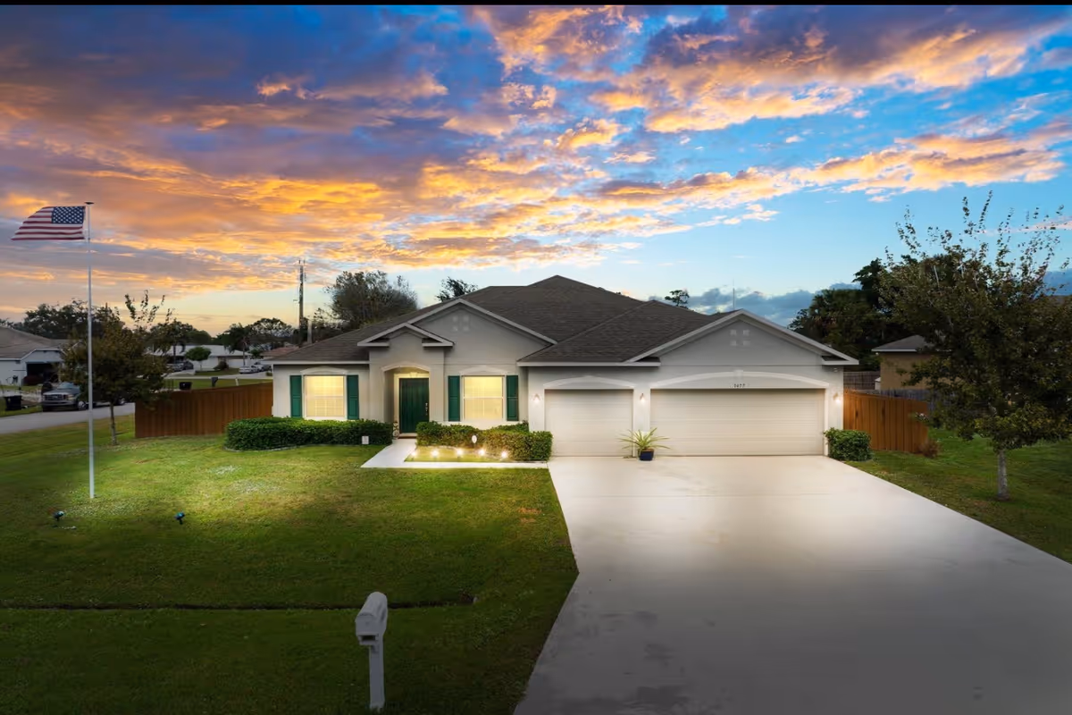 A single-story house with a two-car garage, flagpole, and well-kept lawn.