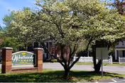 The front exterior of Westbrook Towers shows a sign and trees.