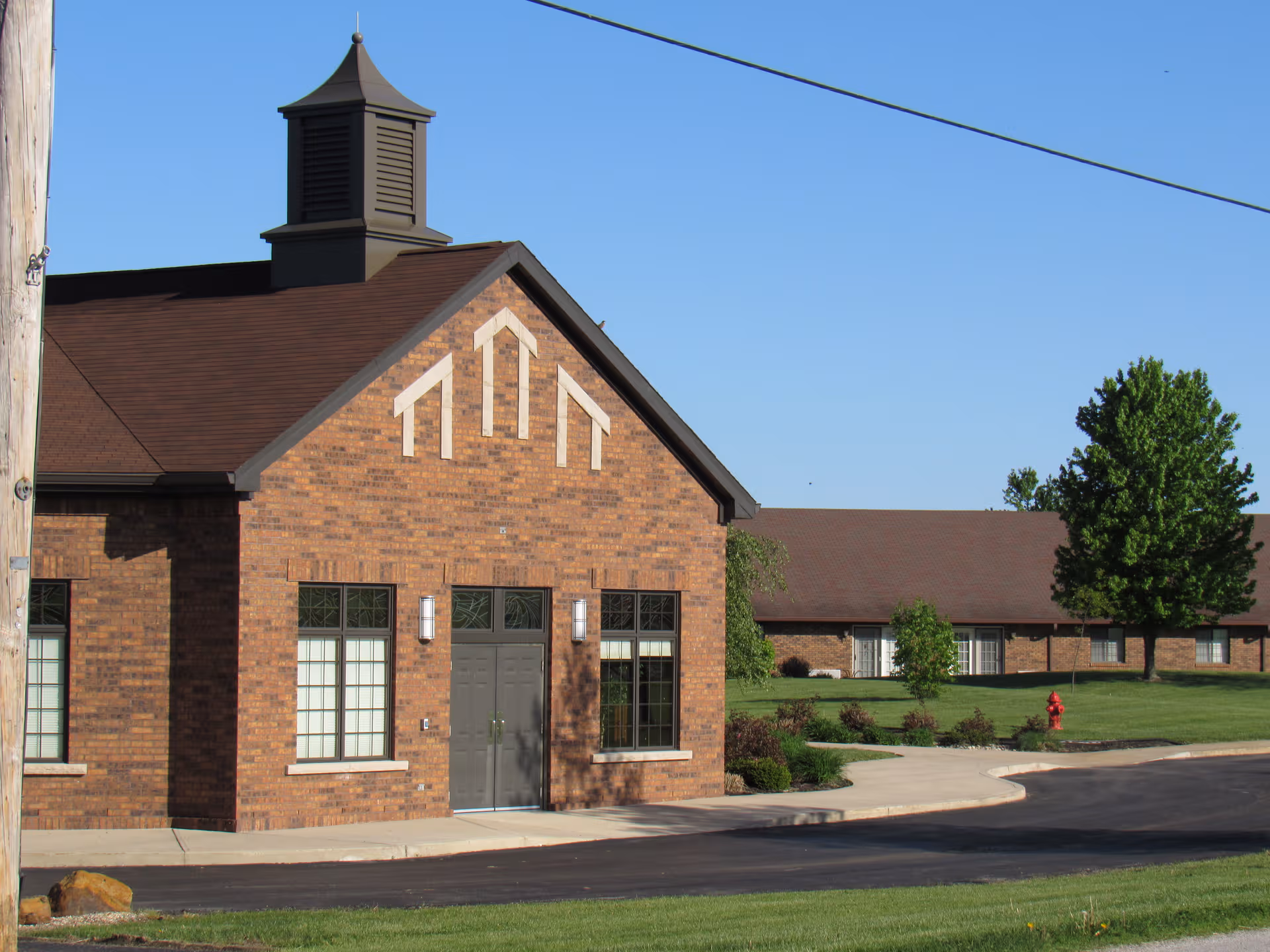 Brick facility with front entrance, decorative gable, and blue sky.