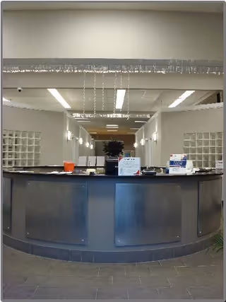 Curved reception desk in a spacious, well-lit lobby with glass block walls.