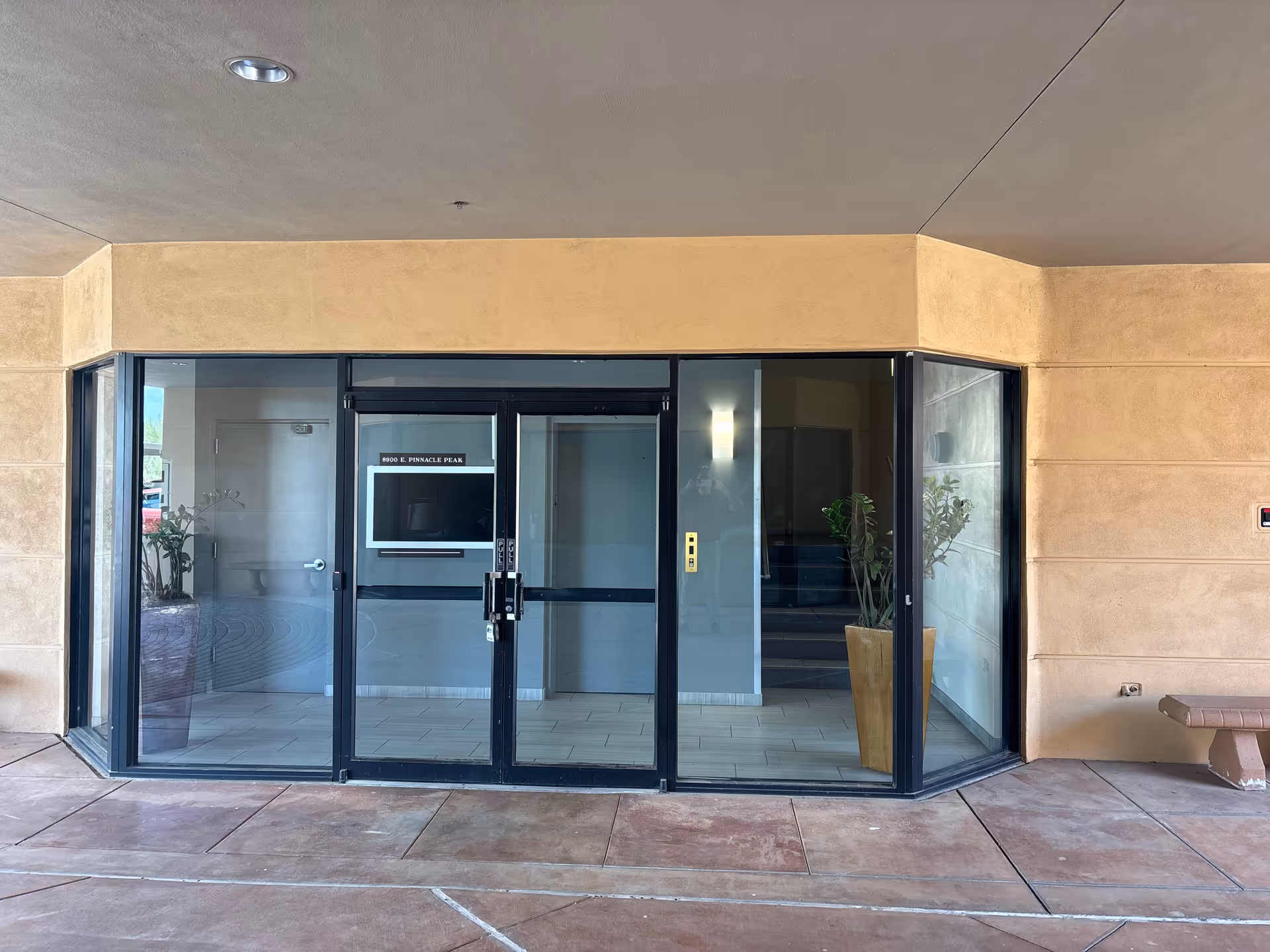 Exterior view of Harvest Home Care entrance with glass doors and potted plants.