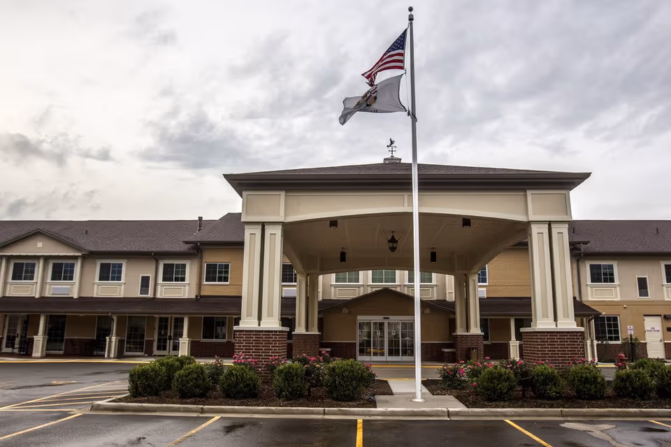Front view of Cedar Lake Assisted Living and Memory Care entrance with flagpoles.