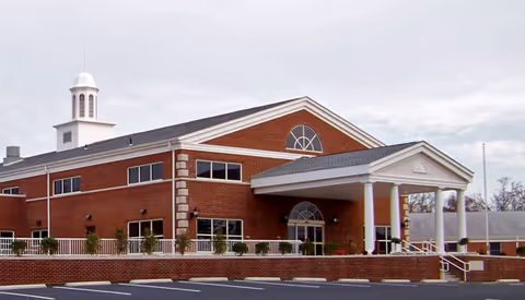 Brick hospital exterior with a covered entrance and surrounding parking lot.