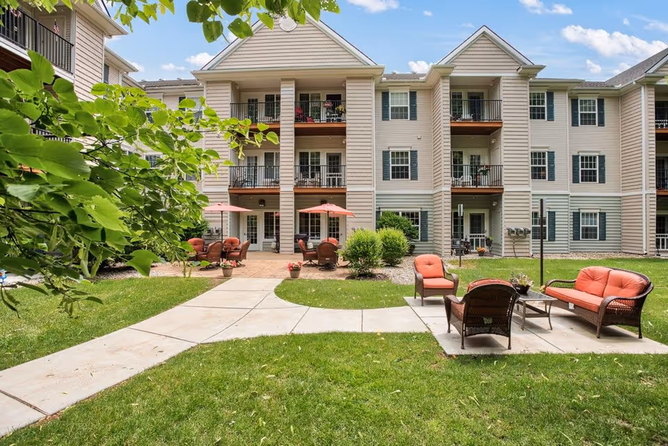 Exterior view of Rose Terrace Cottages with balconies and a patio courtyard with orange seating.