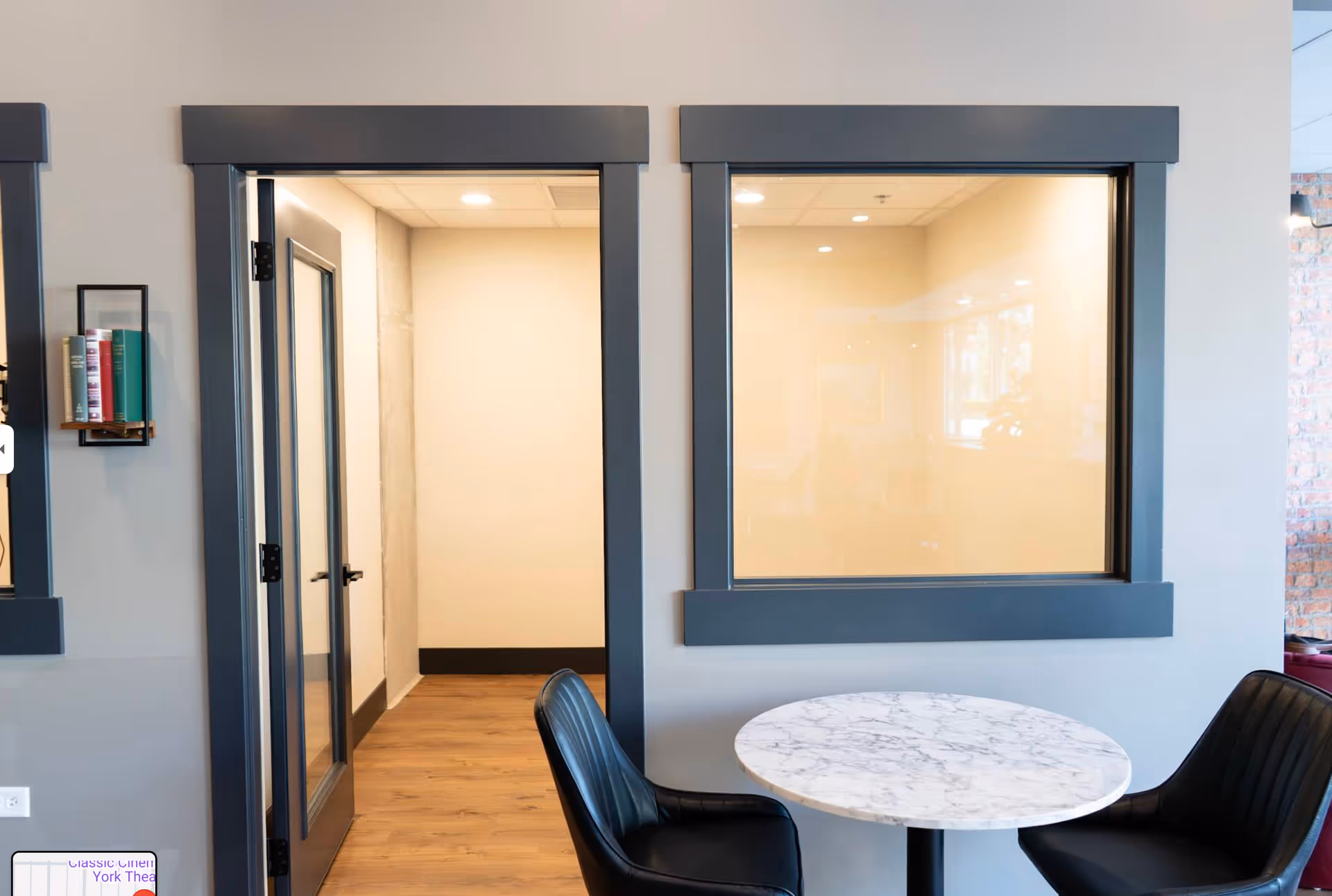 Interior senior living lobby with a round marble table and two black chairs.