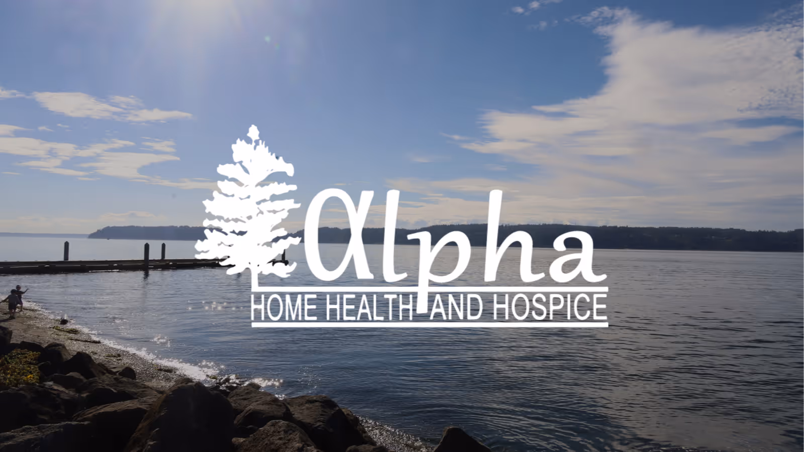Lakeside scene with rocky shore and a dock, overlaid with Alpha Home Health & Hospice logo.