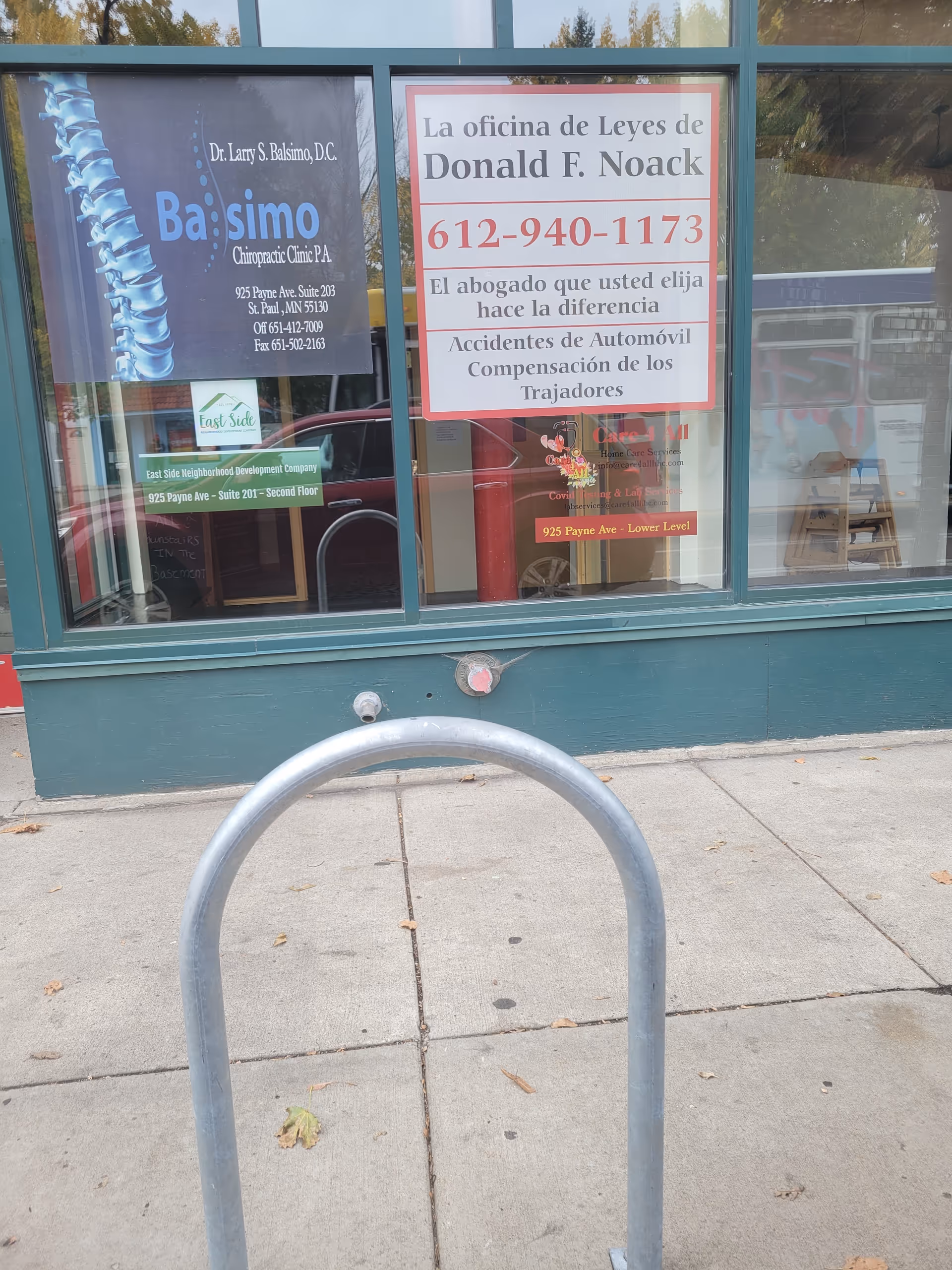 Storefront window with multiple signs and a metal bike rack on the sidewalk.