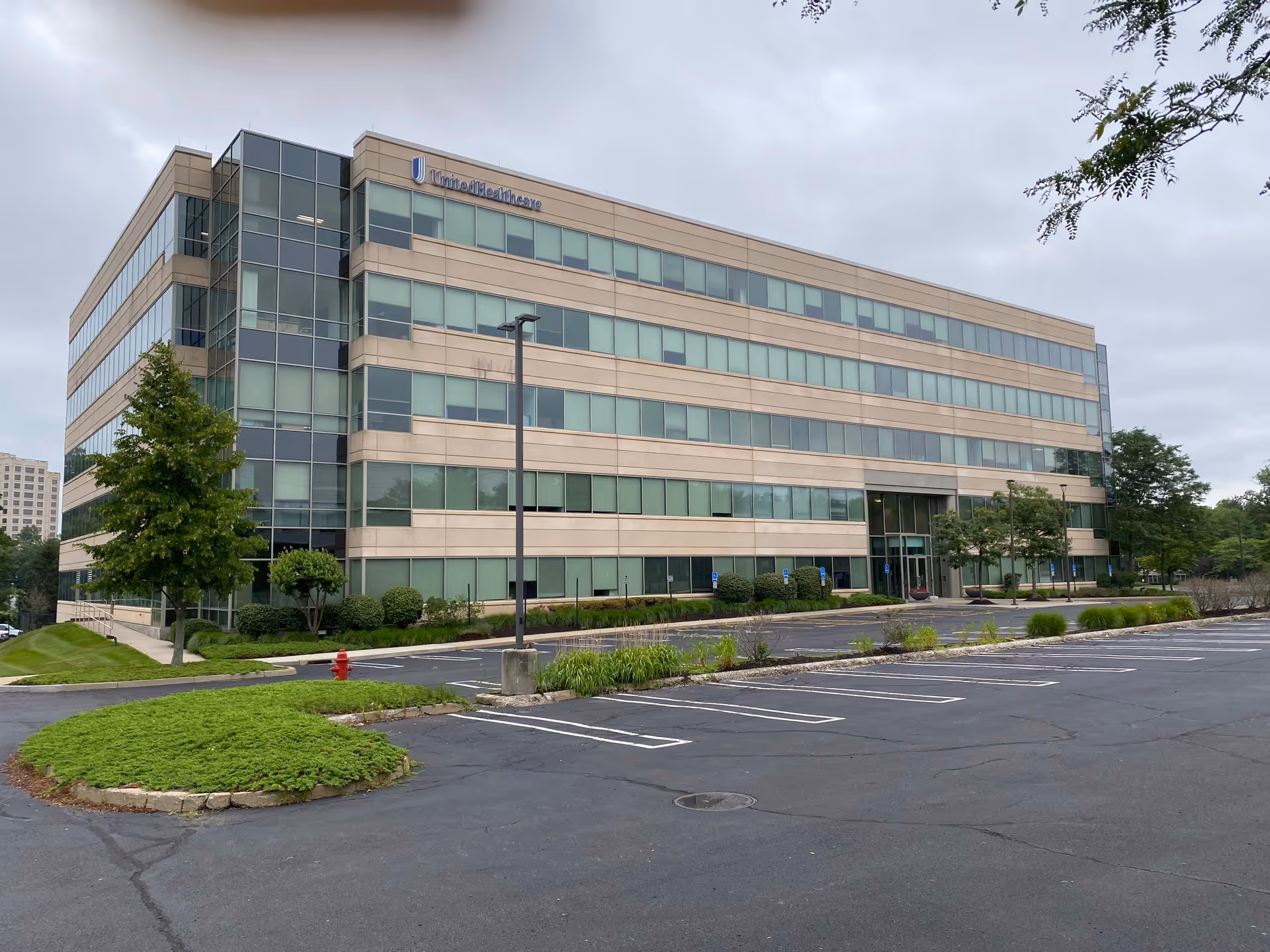 A modern, multi-story office building with a parking lot and greenery.