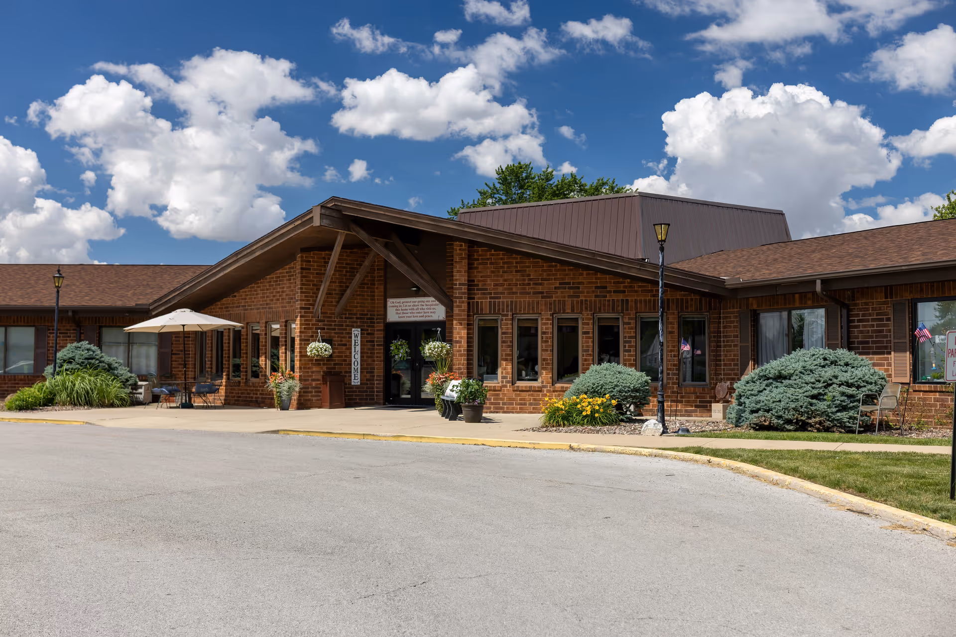 Brick Bethesda Care Center entrance with shrubs, planters, and outdoor seating.
