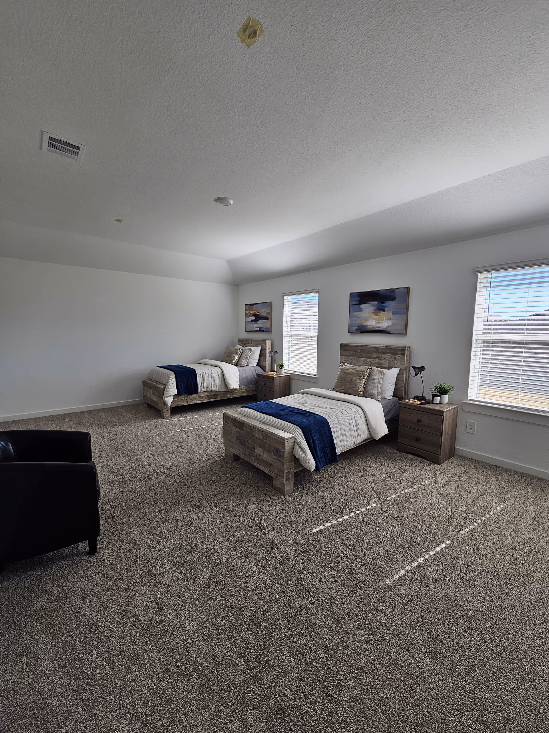 Bright senior living bedroom with two twin beds, nightstands, and large windows.