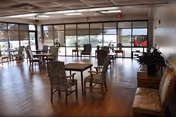 Interior common area of Eunice Manor with tables, chairs, and large windows.