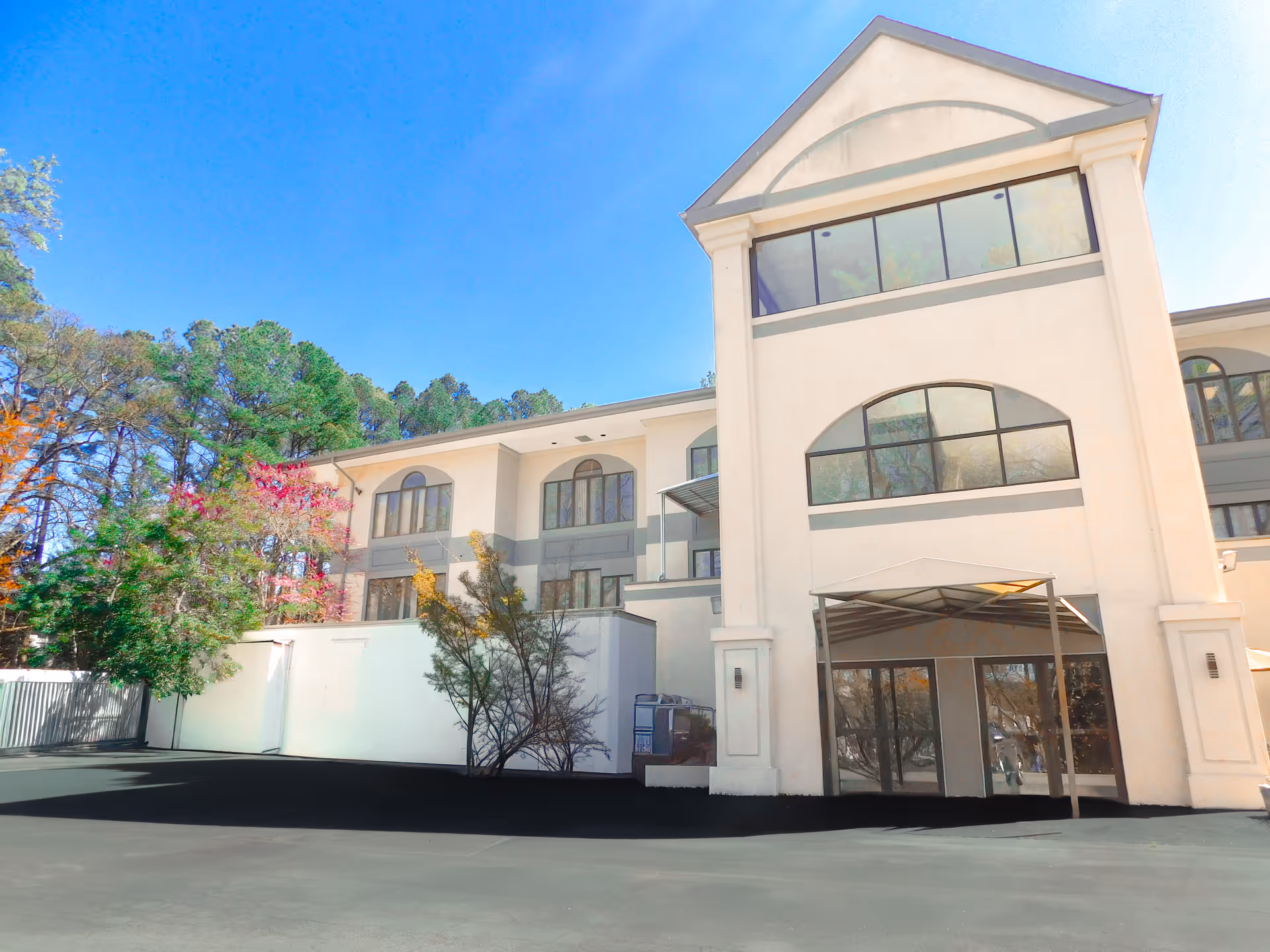 White multi-story senior living facility exterior with arched windows and entrance canopy.
