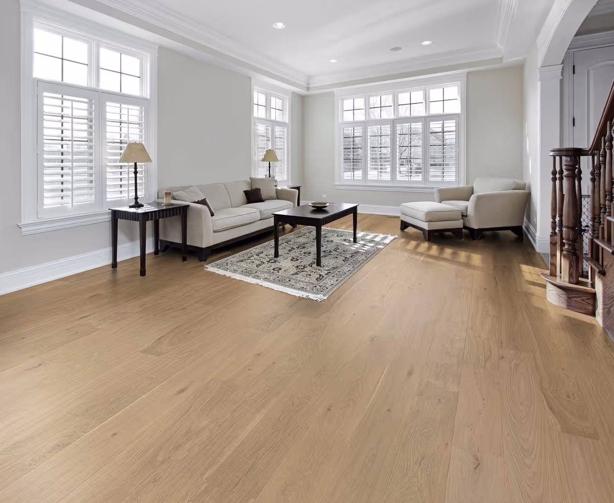 Bright living room with beige furniture, large windows, a rug, and hardwood floors.