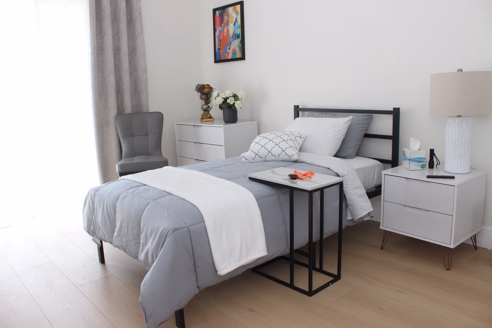 Bright, modern Chatsworth bedroom with a neatly made bed, nightstands, chair, and soft curtains.