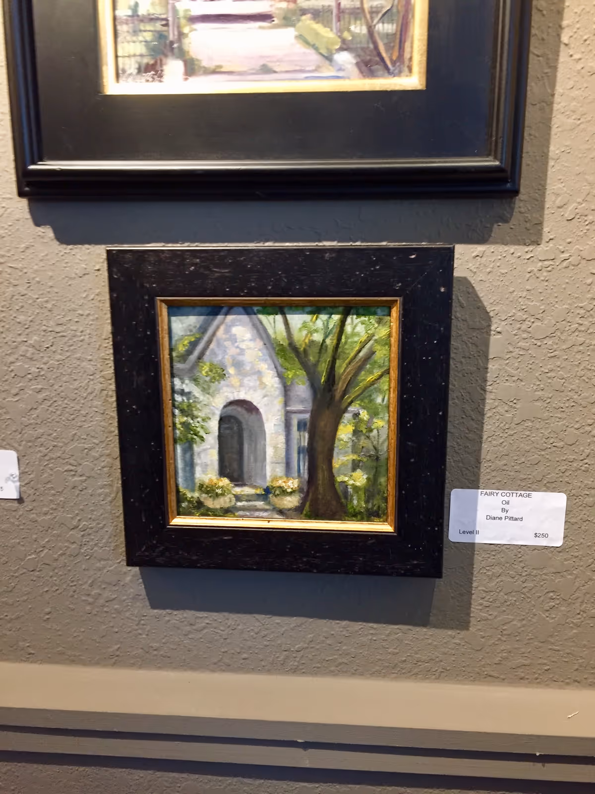 Framed paintings hang on a textured interior wall in a facility hallway.