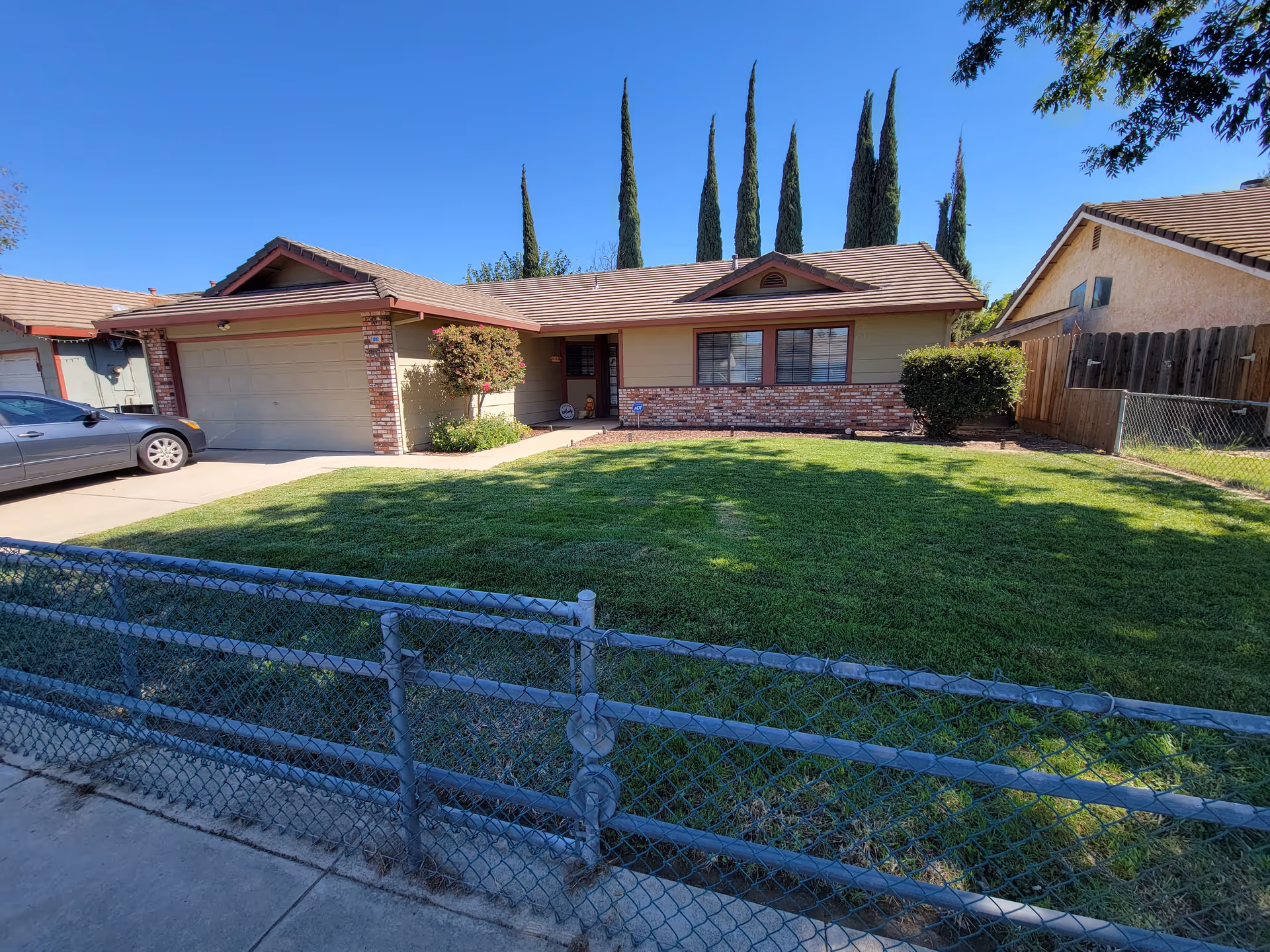Front exterior of a single-story home with a green yard and driveway.