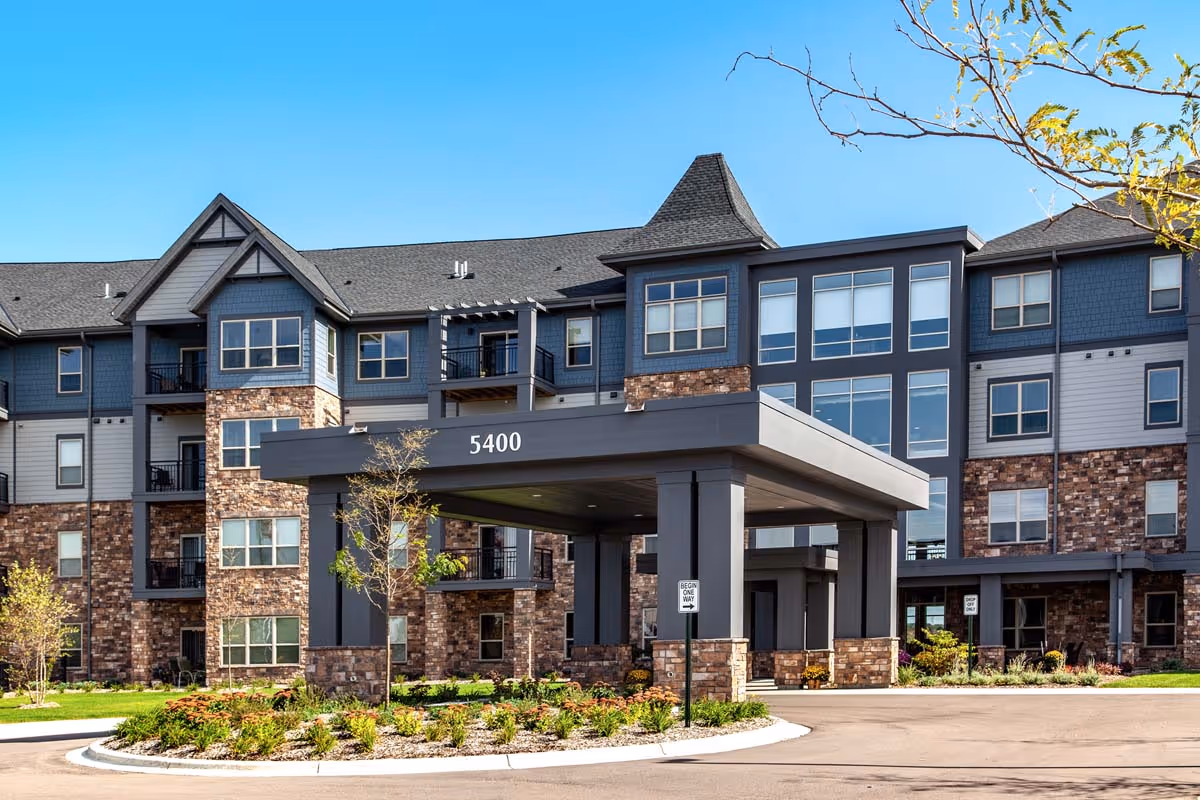 Front exterior of a multi-story residential building with stone facade and a covered entrance canopy marked "5400".