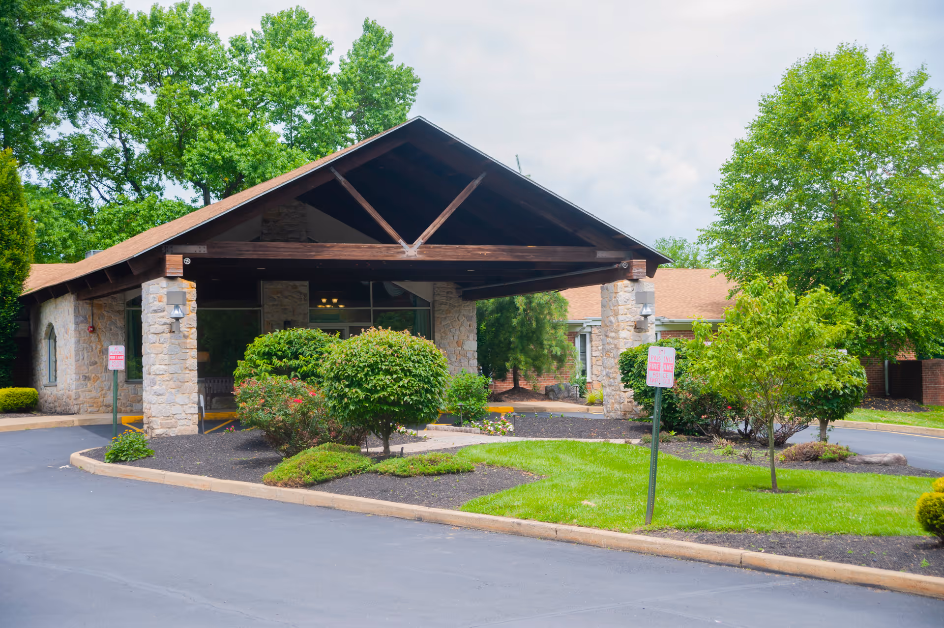 Stone building entrance with wooden peaked canopy and manicured landscaping.