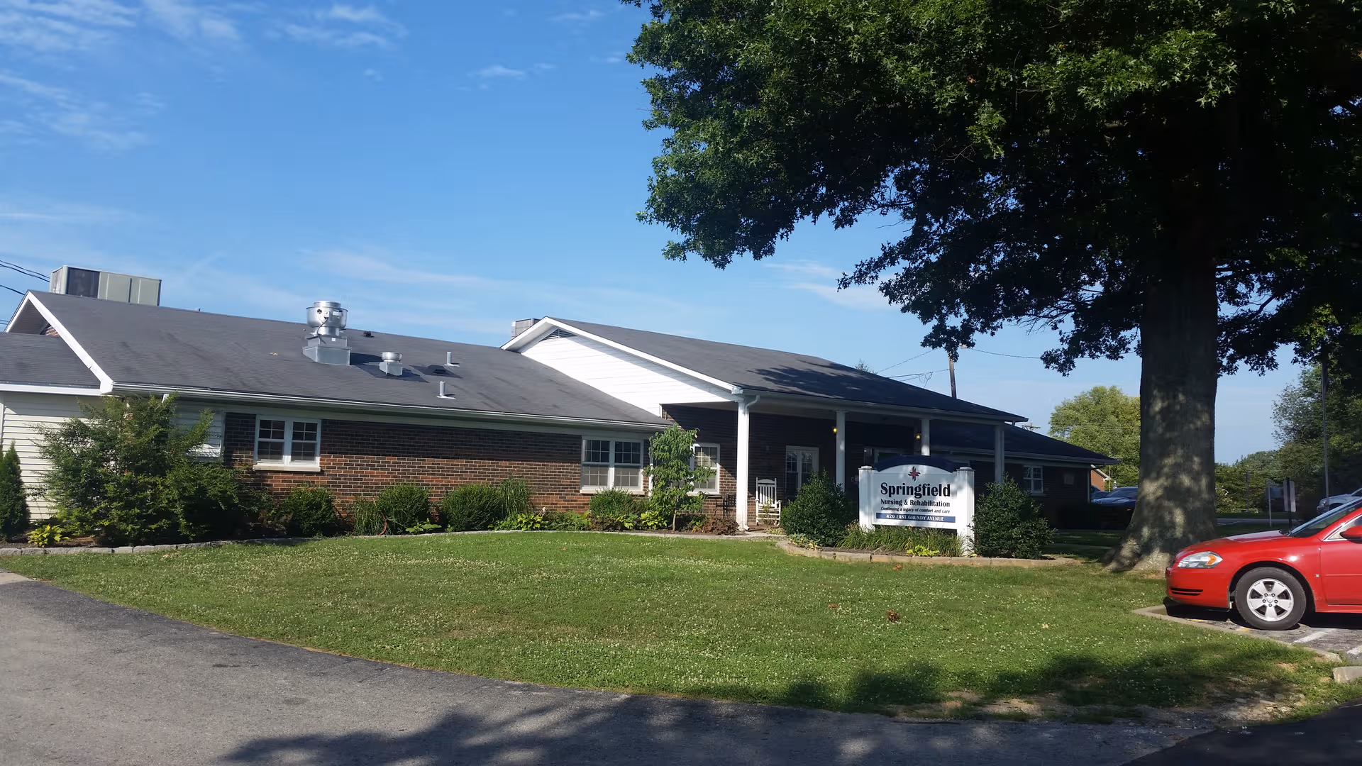 One-story Springfield Nursing and Rehabilitation Center exterior with a sign, landscaping, and a red car nearby.