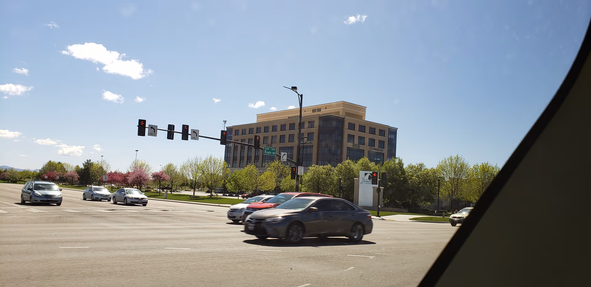 Wide street intersection with traffic lights and a modern building in the distance.