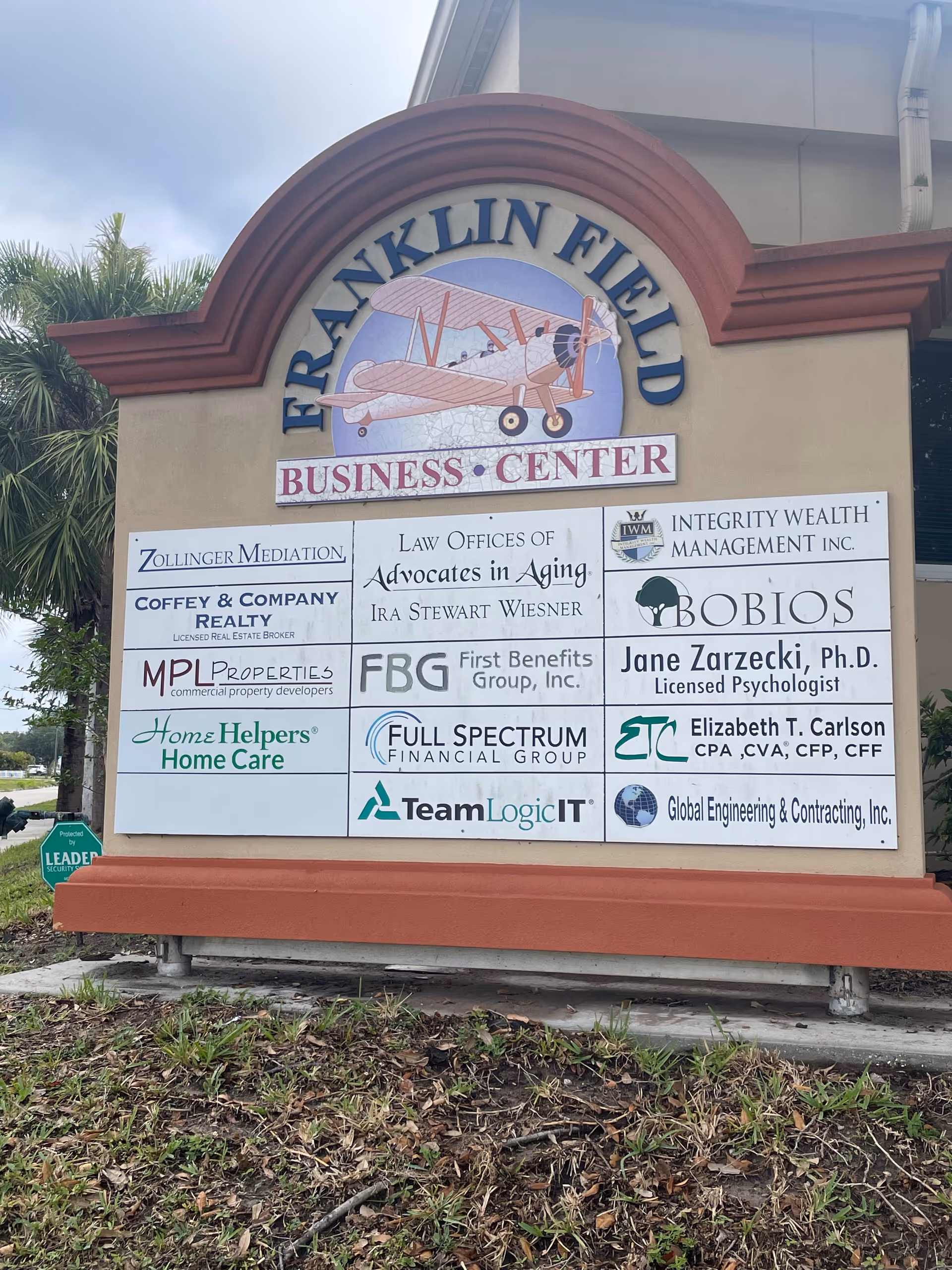 Exterior building signboard displaying multiple business logos including Home Helpers Home Care in Sarasota