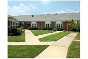 Front exterior of Wellington Parc of Owensboro, brick building with walkways and a green lawn.