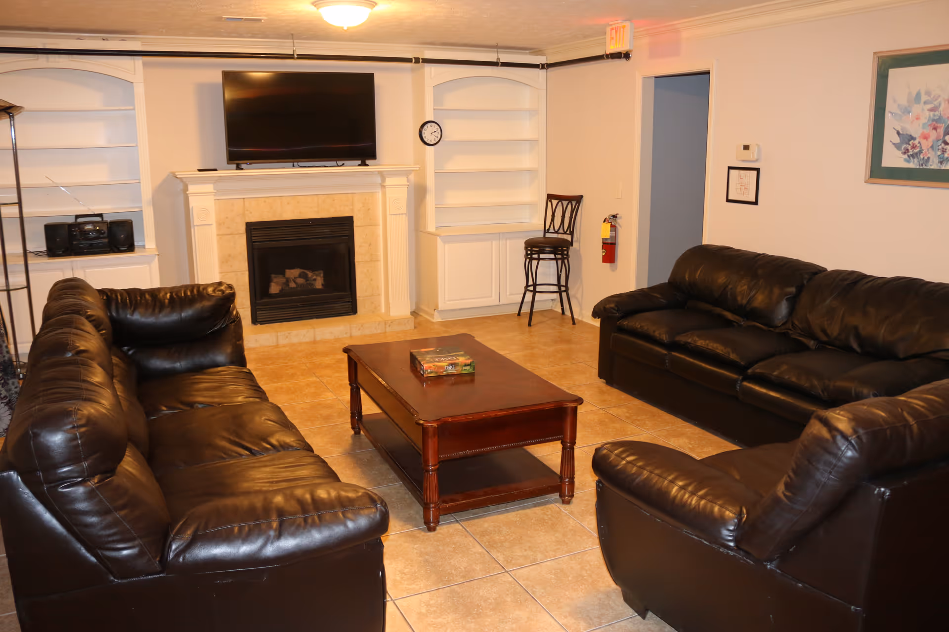 Living room with leather sofas, coffee table, fireplace, and built-in white shelves.