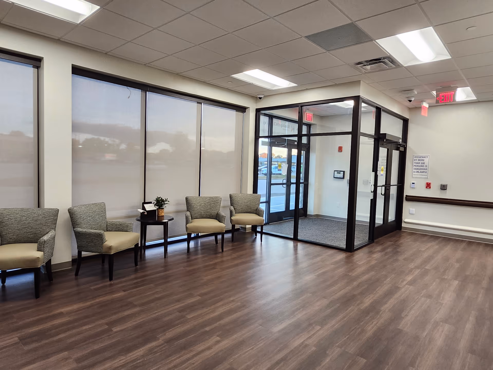 Lobby seating area with glass entry doors and large windows in a senior facility.