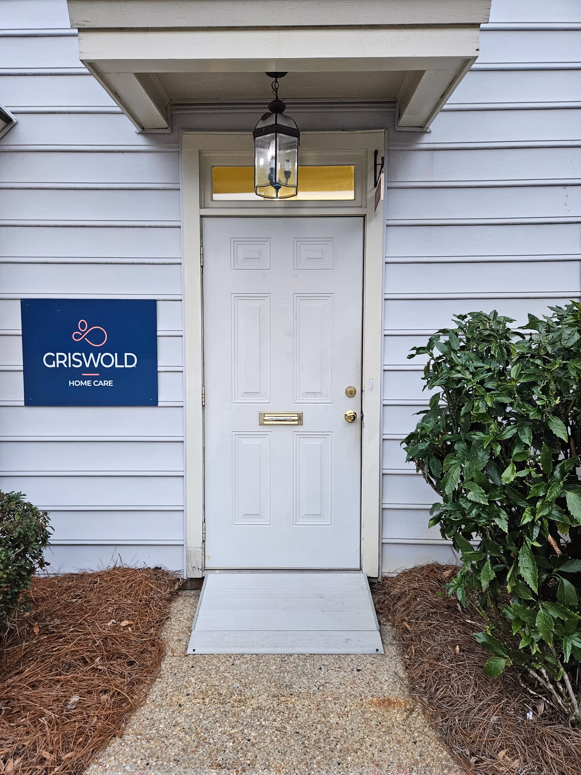 Front entrance of Griswold Home Care for Wilmington with a hanging lantern above a white door.