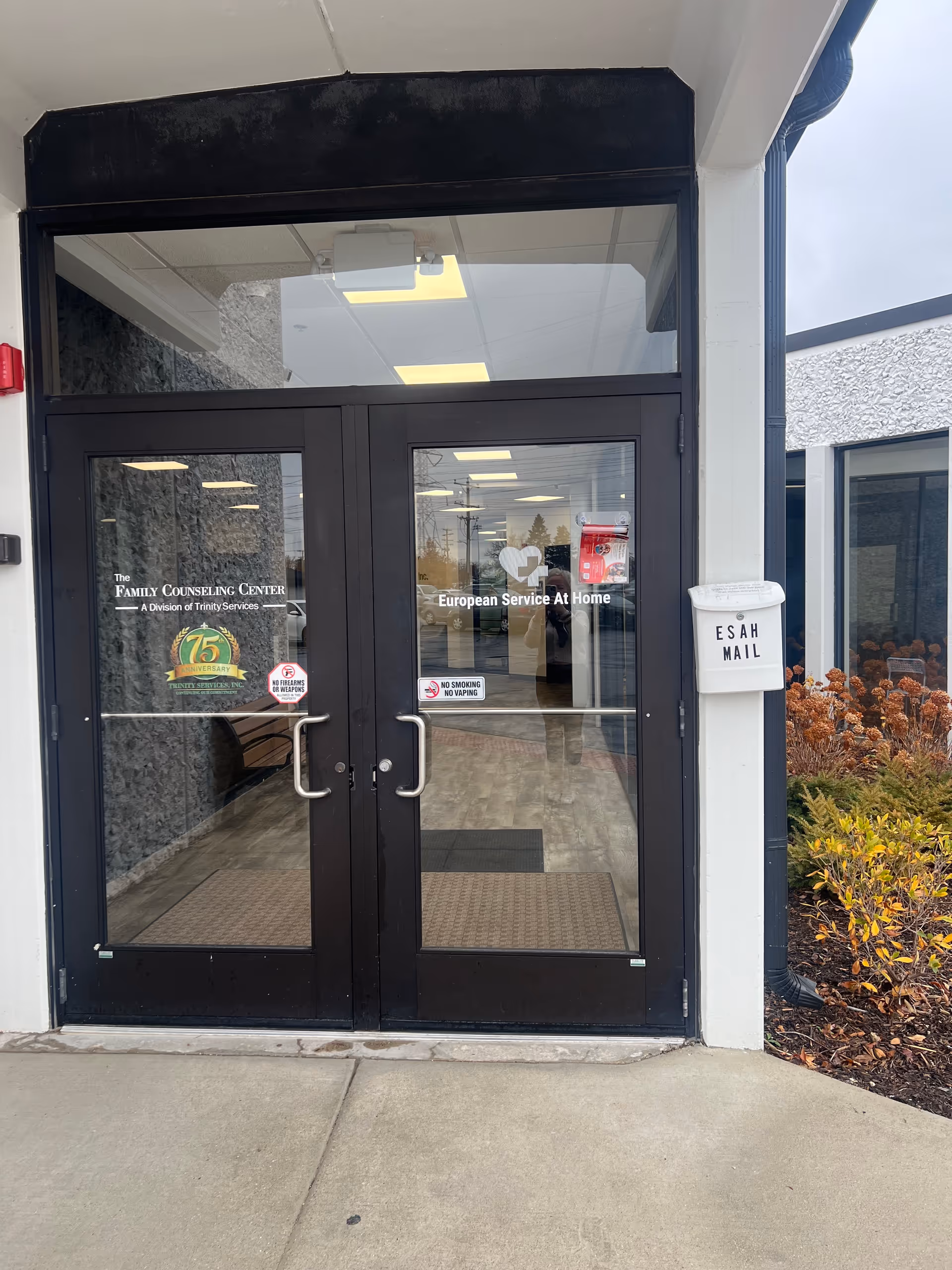 Front double glass doors with signage 'European Service At Home' and a nearby mailbox.