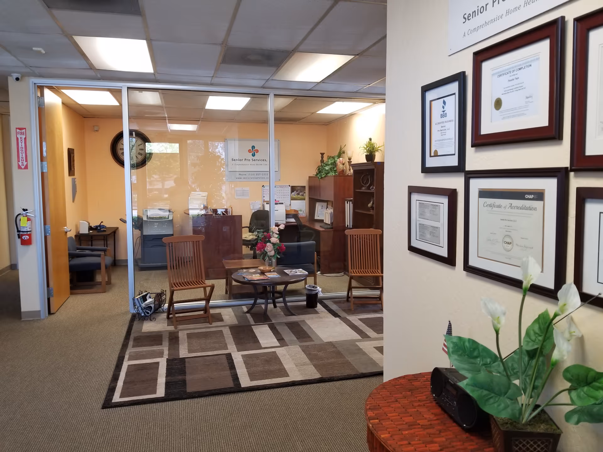 Office lobby of Senior Pro Services with chairs, glass walls, certificates, and plants.