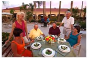 Group of seniors dining outdoors around a table with plated meals.