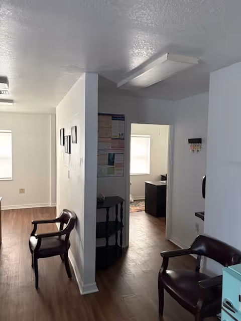 Interior of a senior living facility with chairs along a wall and doorway to a room.