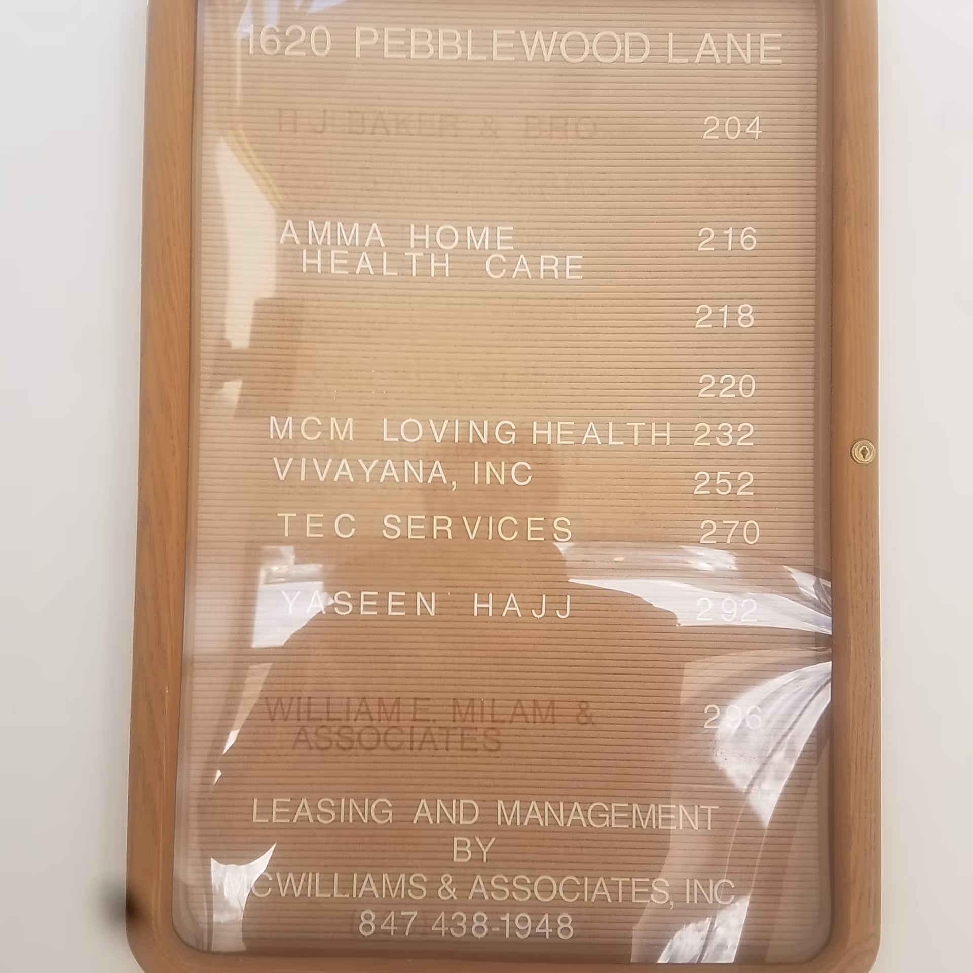 Wood-framed interior directory sign listing Amma Home Health Care and tenants.