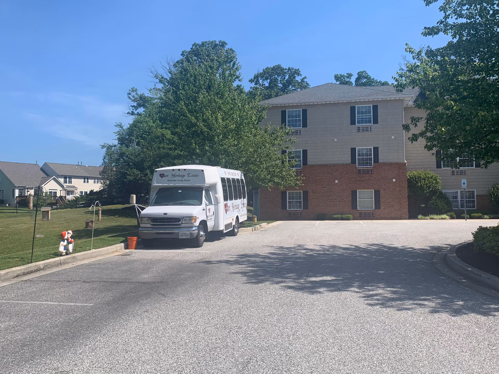 Hart Heritage Estates bus parked in a lot beside a two-story beige building.