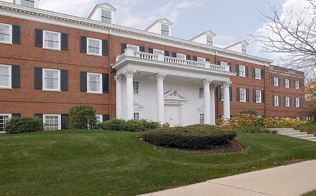 Brick senior living facility with white columns and manicured lawn.