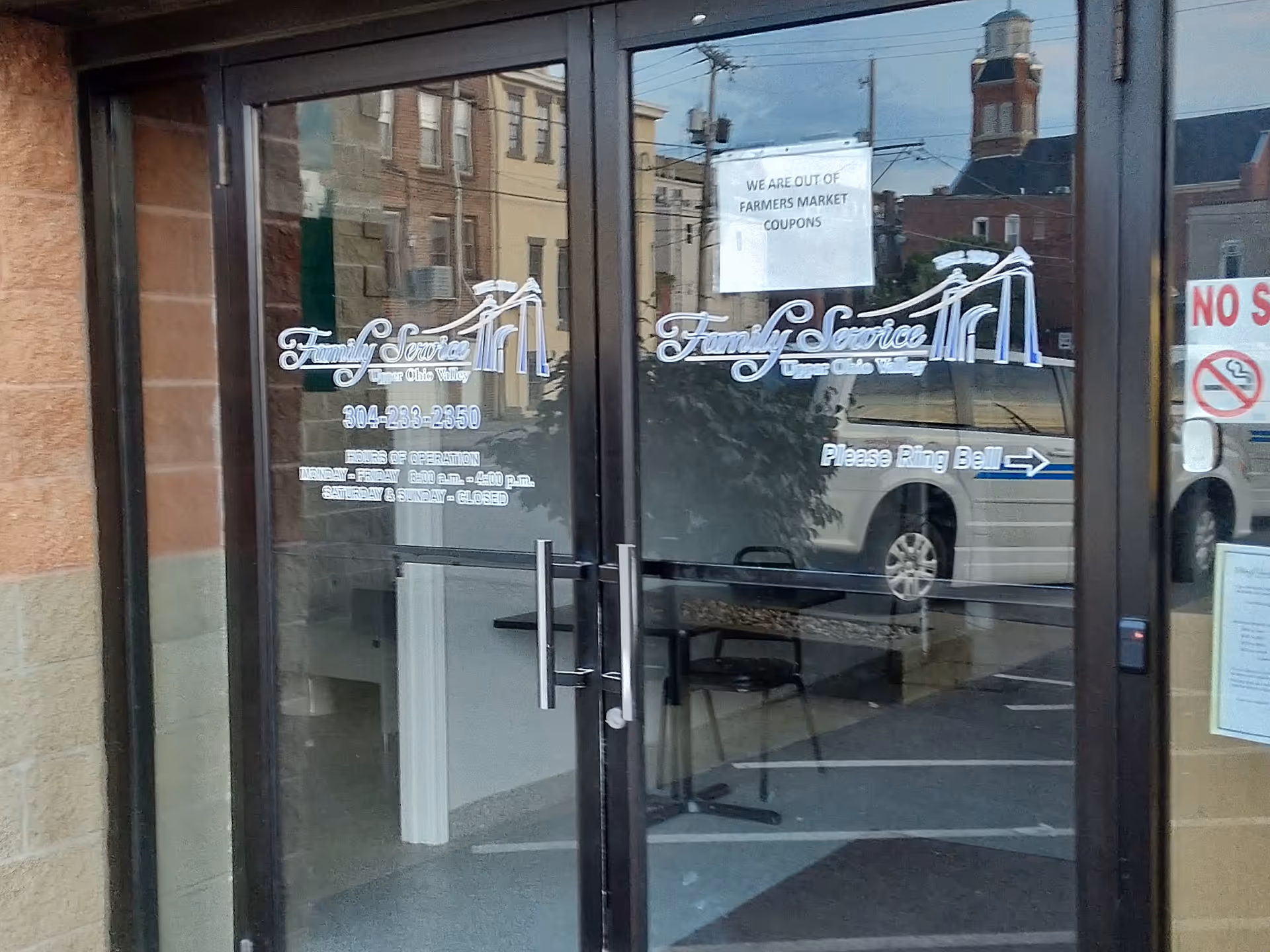 Glass doors display Family Service signage with street reflections and a parked van visible.