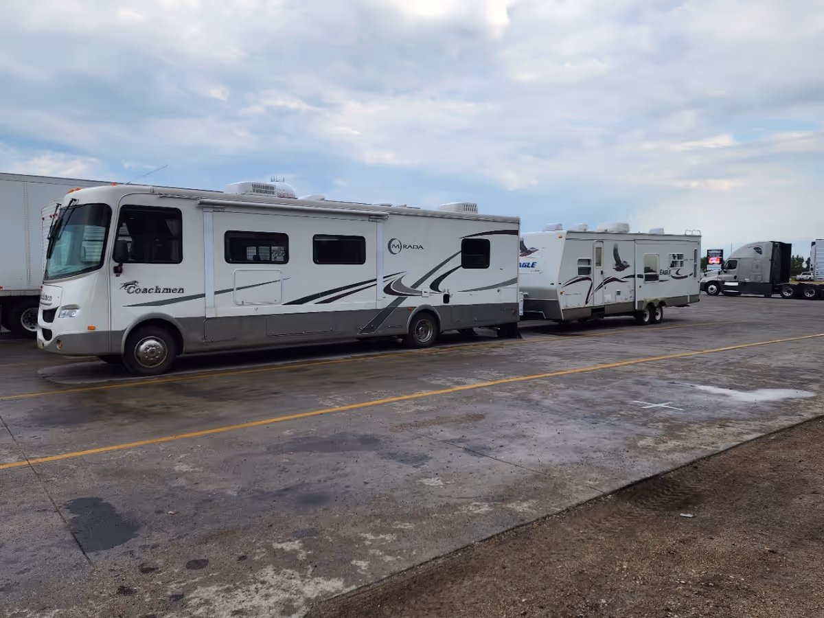 Line of large recreational vehicles parked in a lot under a cloudy sky