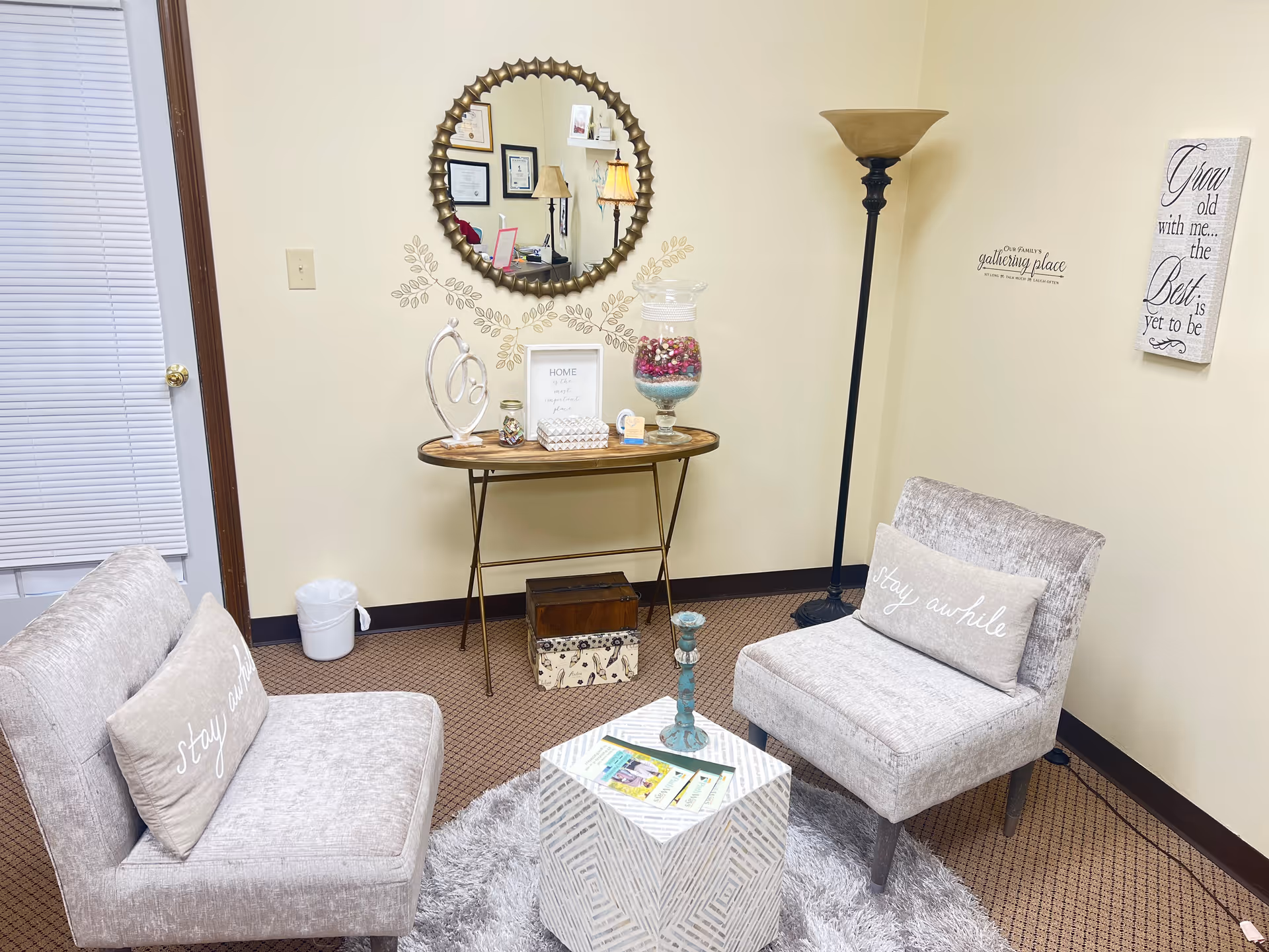 Cozy waiting lounge with two gray armchairs, a small coffee table, and decorative wall art.