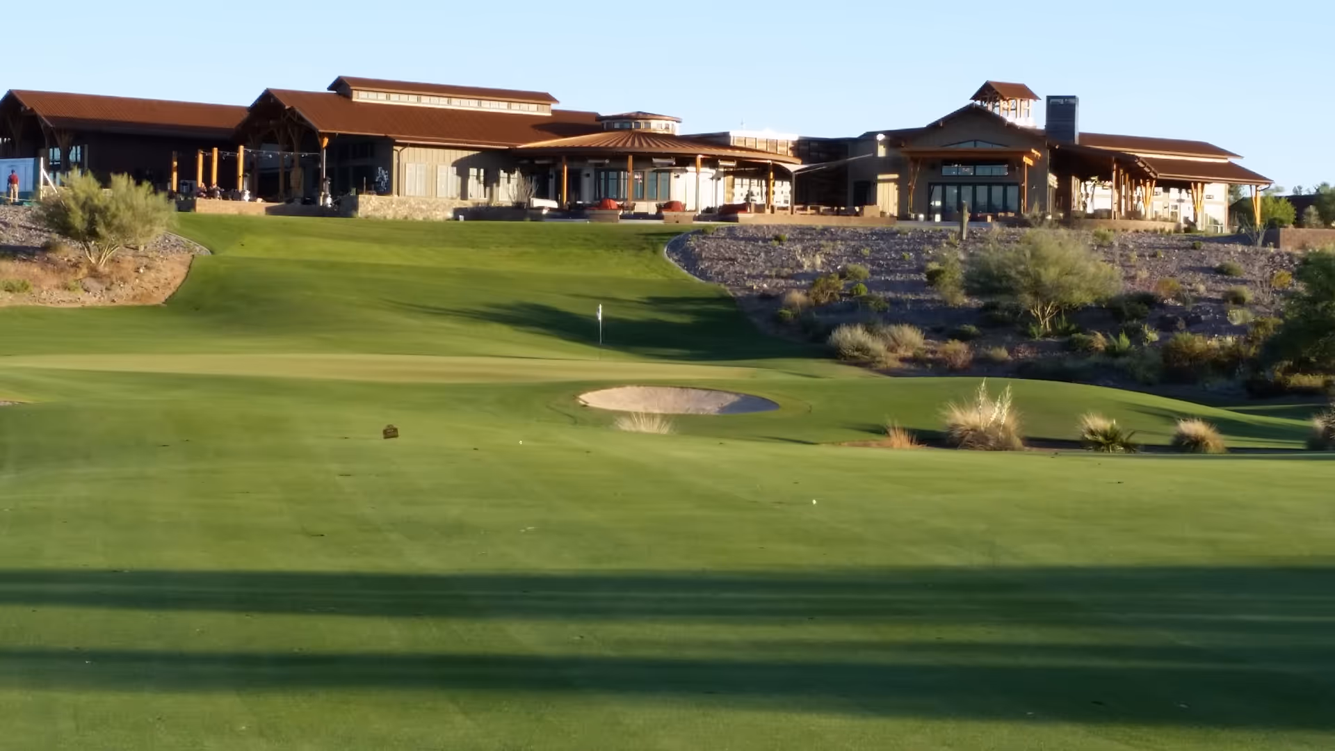 Exterior view of Trilogy at Wickenburg Ranch with a green golf course and building in background.