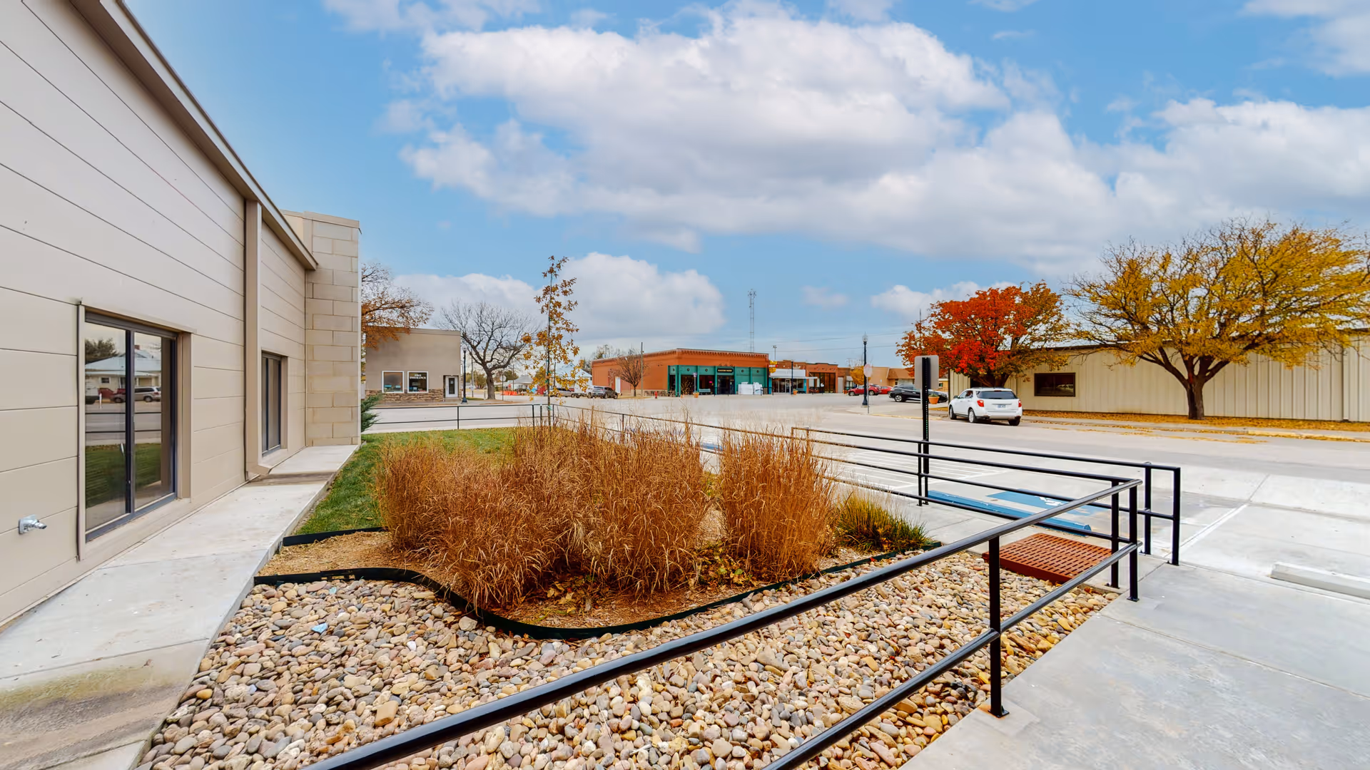 Exterior view of a senior living facility with a ramp, gravel beds, and a parking lot.