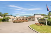 Exterior view of Candlewood Valley Health & Rehabilitation Center with driveway, landscaping, and flag.