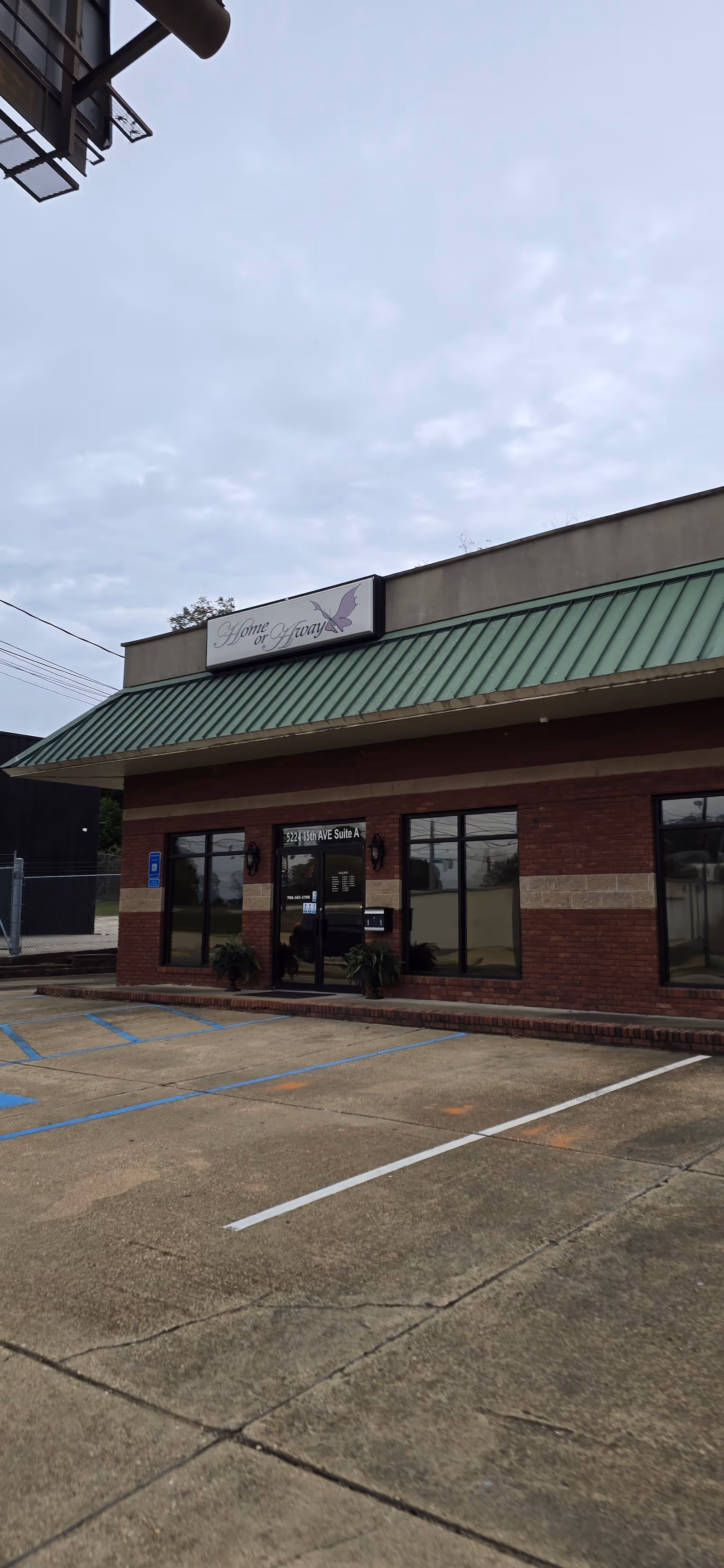 Exterior view of Home or Away senior living facility with glass entrance and parking