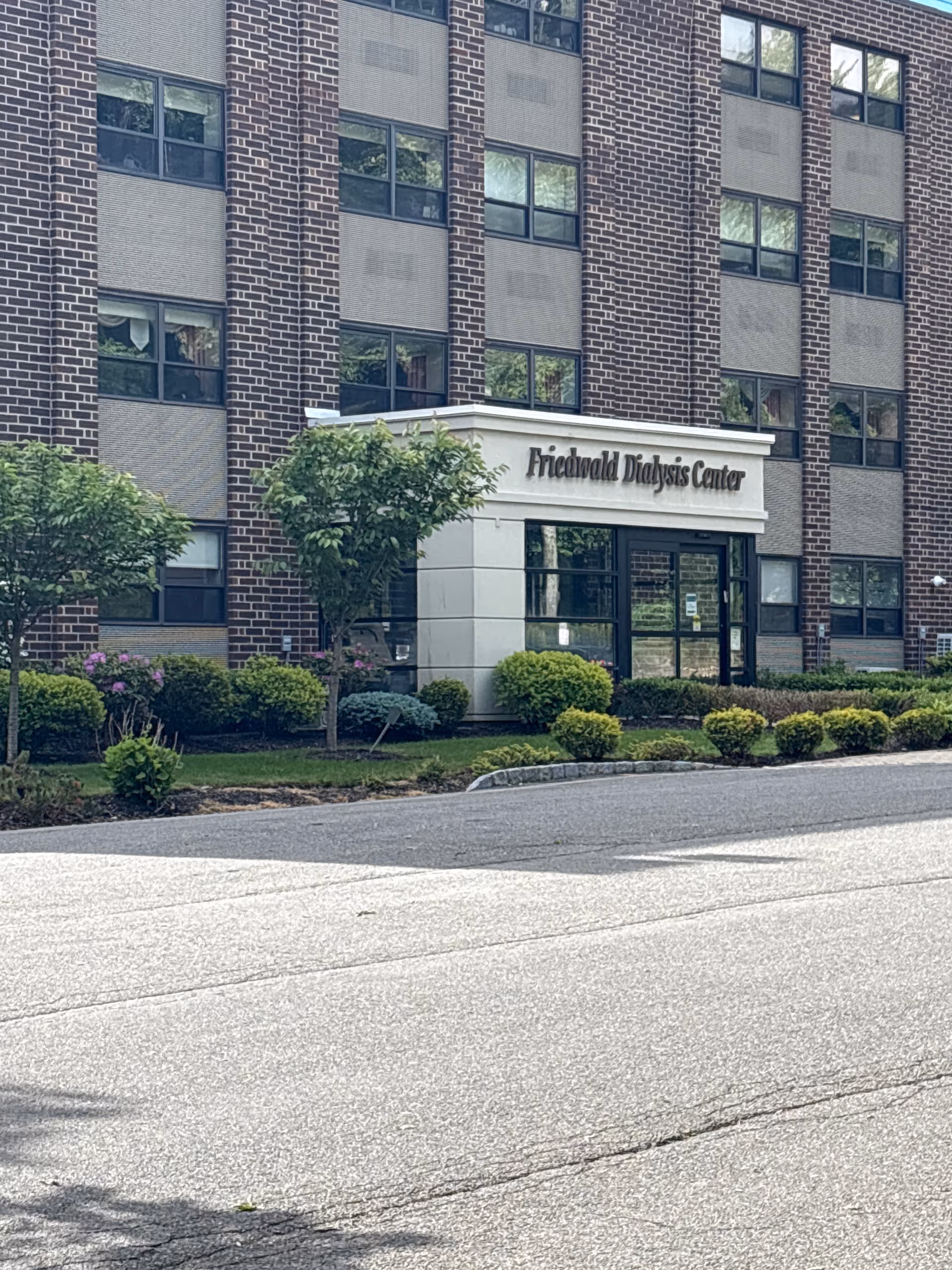 Brick multi-story senior living building with Friedwald Dialysis Center entrance and landscaped front.
