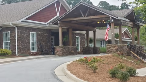 Exterior of a senior living facility with a covered entry and flag.