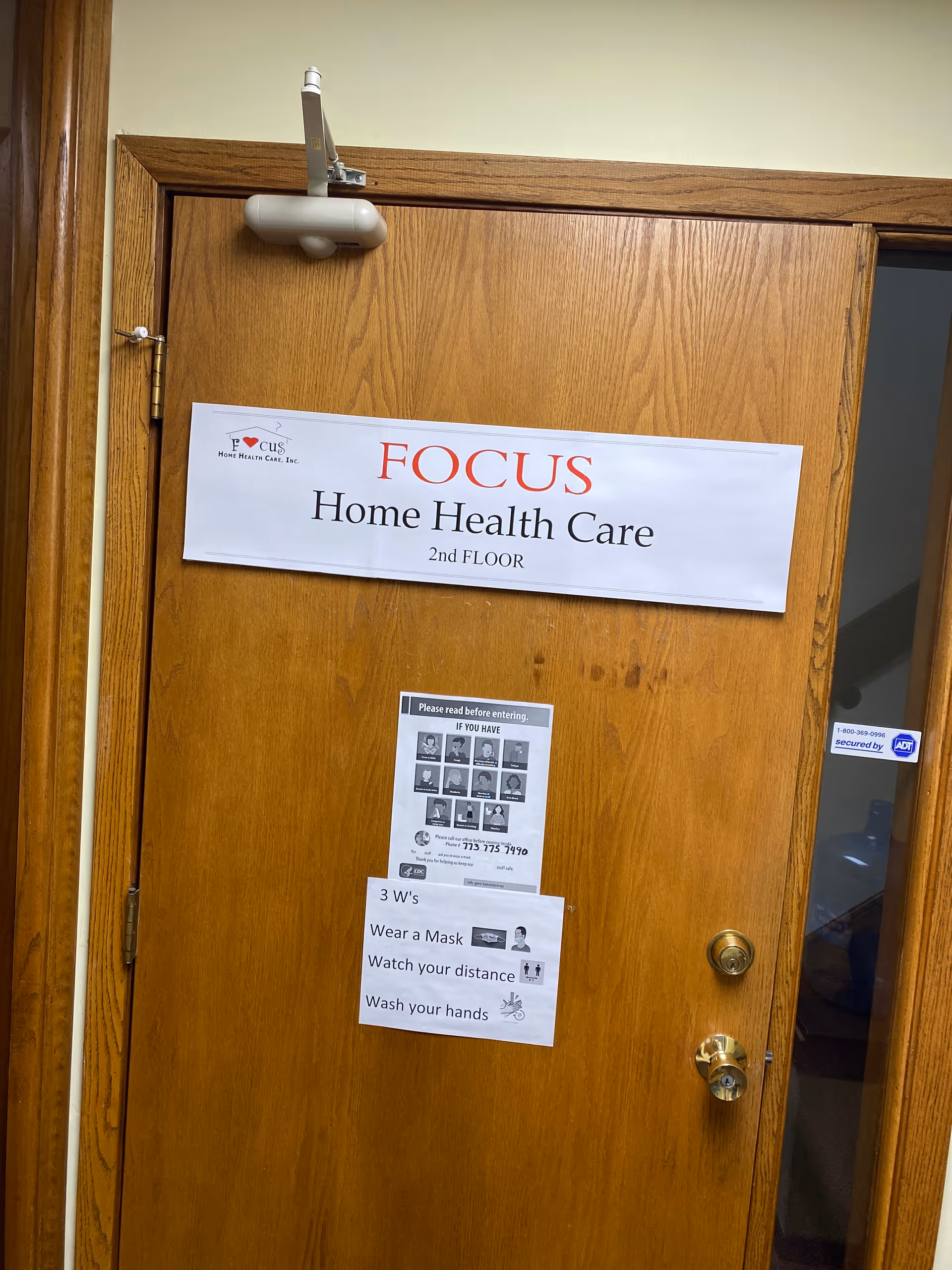 A wooden interior door with Focus Home Health Care signage and health notices posted.